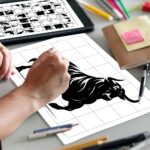 A person's hands finishing a grid drawing puzzle of a bull, copying the squares from the instruction sheet placed next to the drawing on the table.