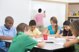 Three students working on educational drawing puzzles, while three other children are engaged in grid drawing activities for students, focusing on their worksheets.